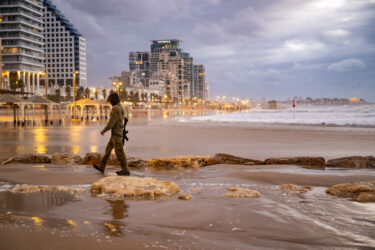 TEL AVIV, ISRAEL - NOVEMBER 27: An IDF reservist walks along the sand at the beach on the fourth day of the temporary truce between Israel and Hamas on 27/11/2023 in Tel Aviv, Israel. A temporary truce between Israel and Hamas began on Friday, followed by the return of some Hamas-held hostages as well as the release of Palestinian prisoners. If the truce holds, around 50 Israeli hostages are to be released, among the approximate 240 that Israeli authorities say Hamas took captive during its Oct. 7 attack. (Photo by Alexi J. Rosenfeld/Getty Images)