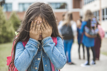Sad Teenage girl outside the school with student on the back