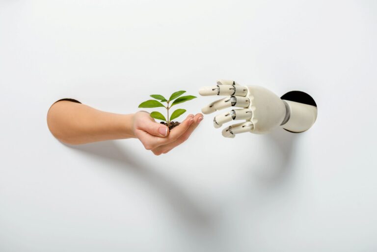 "A human hand holding a small seedling with soil, reaching out toward a white robotic hand emerging from a white wall. The image symbolizes the connection between nature and technology."